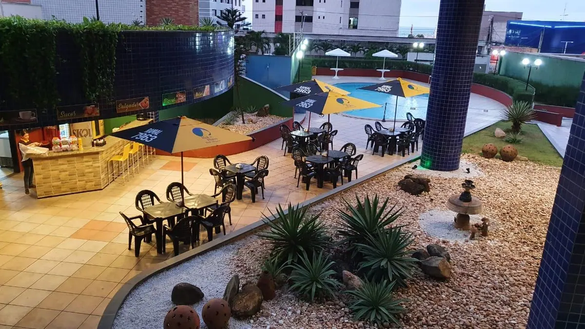 Zona de ocio del condominio al atardecer, con mesas, el bar y la pista al fondo