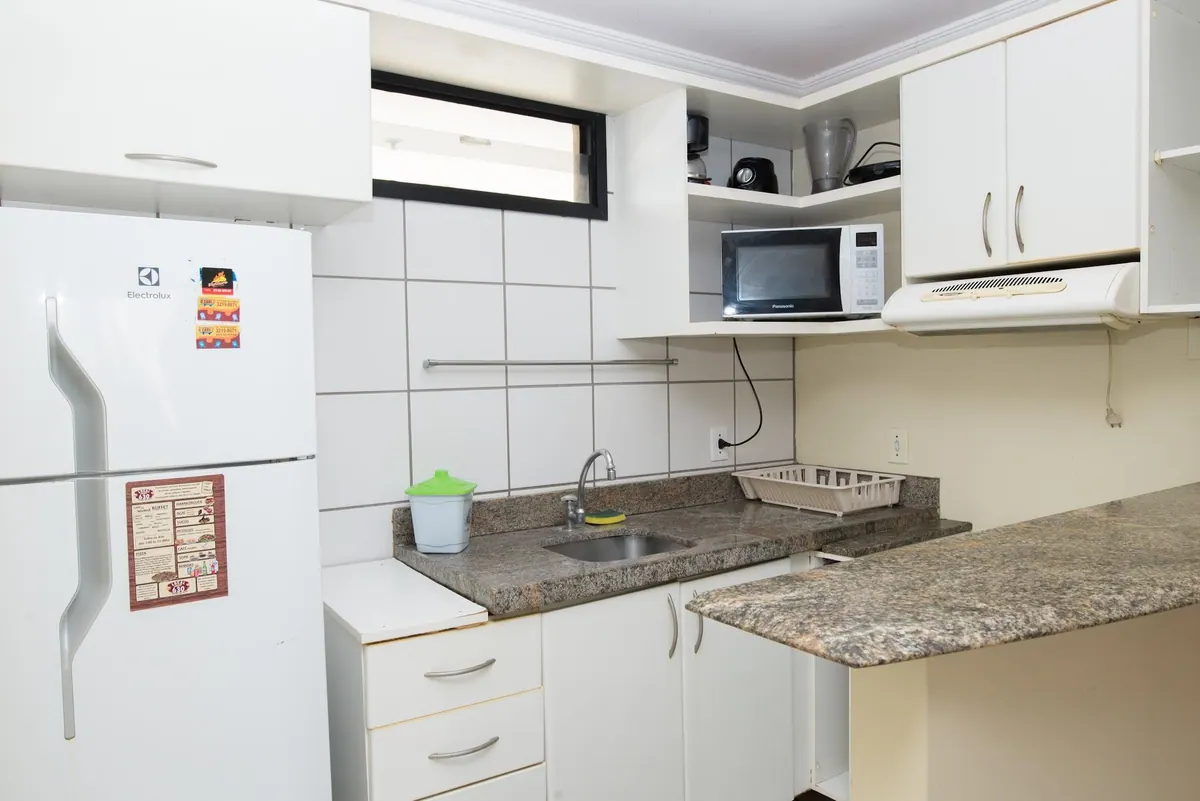 Cocina equipada con nevera, microondas, fregadero y armarios