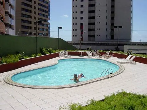 Piscina del condominio vista desde arriba, con tumbonas alrededor