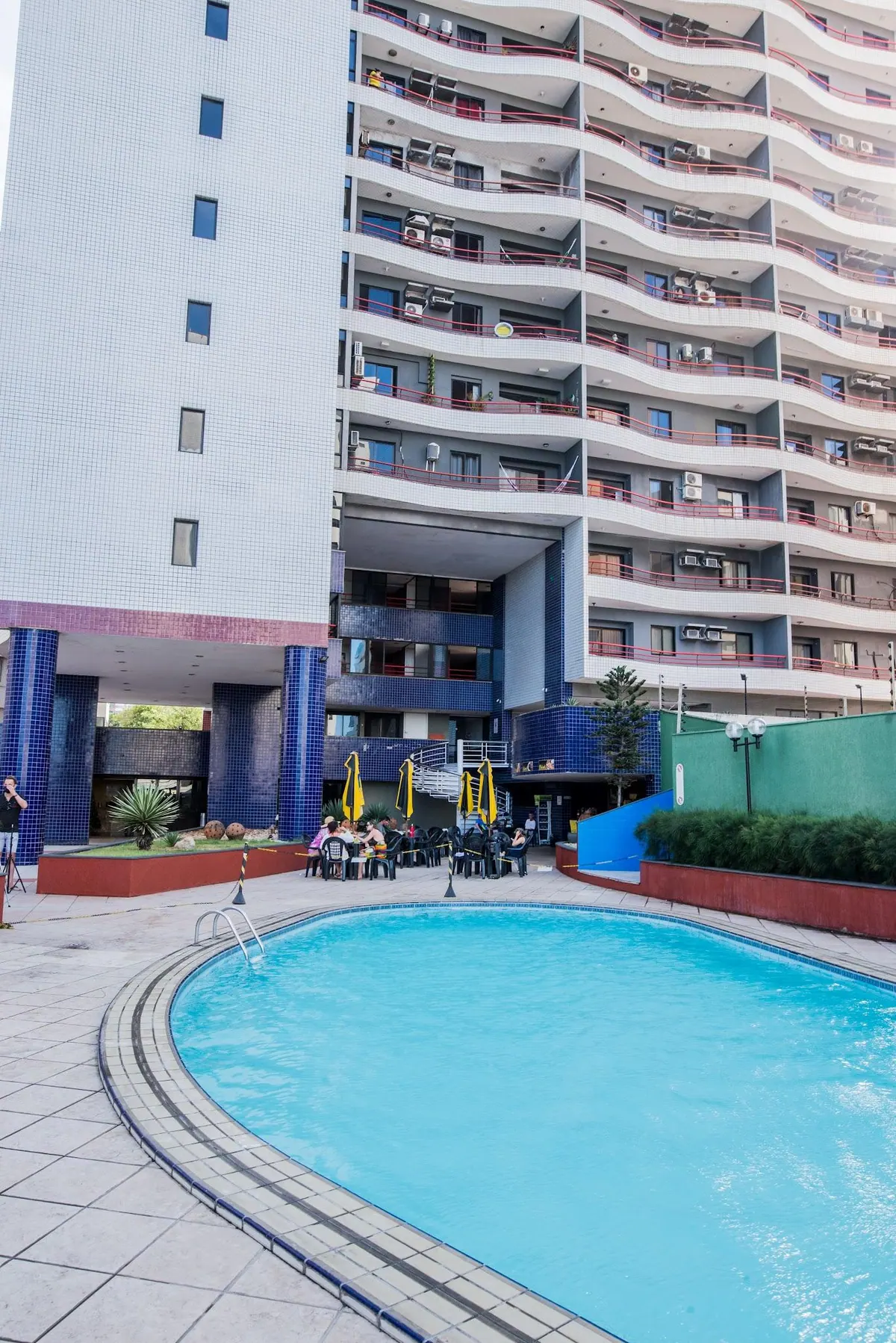 Piscina al aire libre del Condomínio Porto de Iracema con la torre de apartamentos al fondo