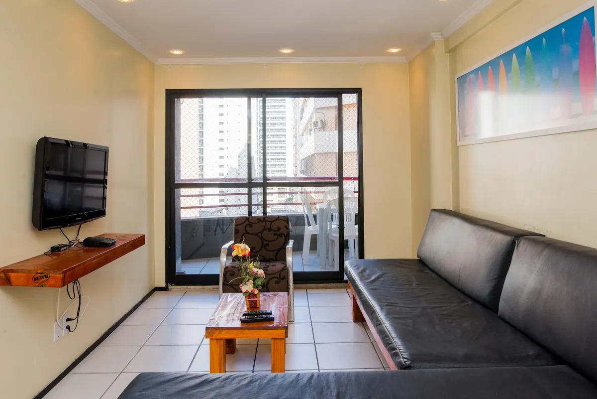 Salón con sofá cama, televisor de pantalla plana y puerta al balcón